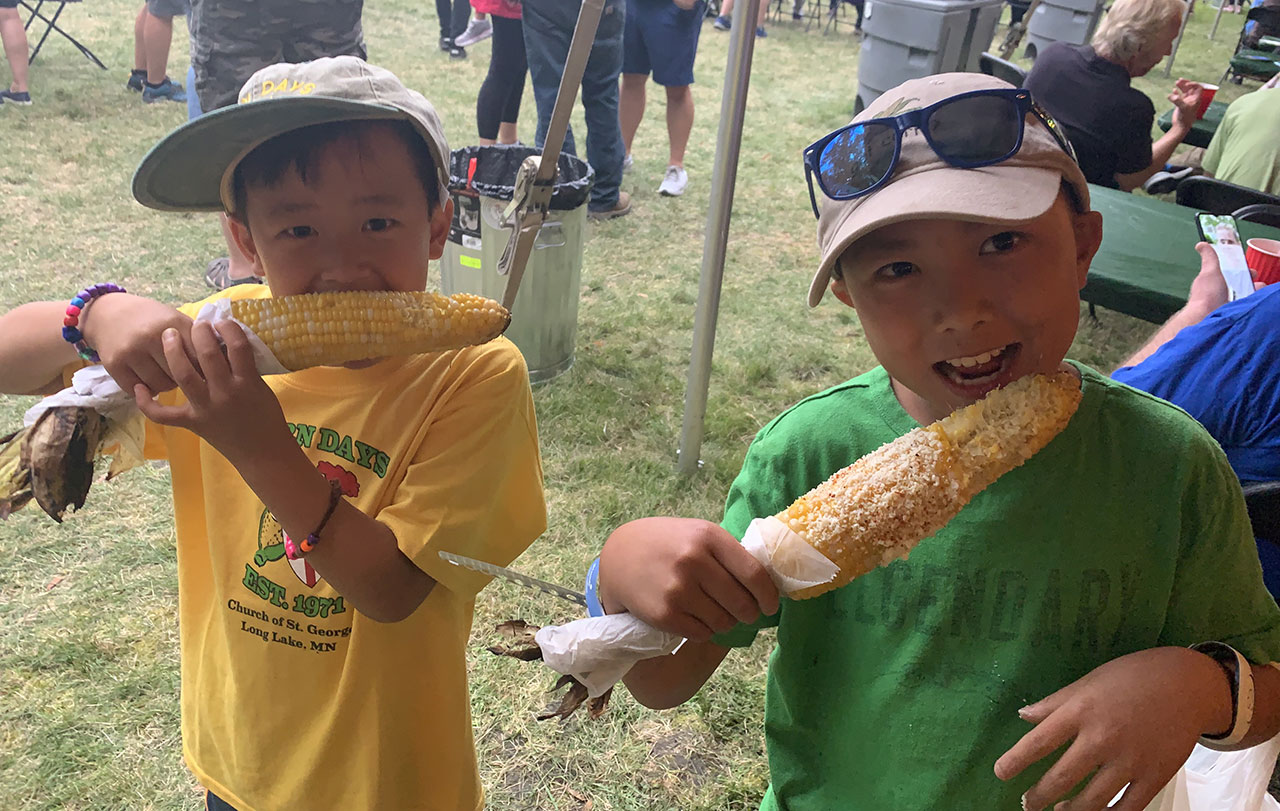 Young boys eating corn at Corn Days